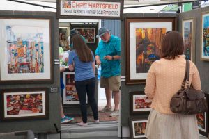 people browsing a vendor booth at the art fair